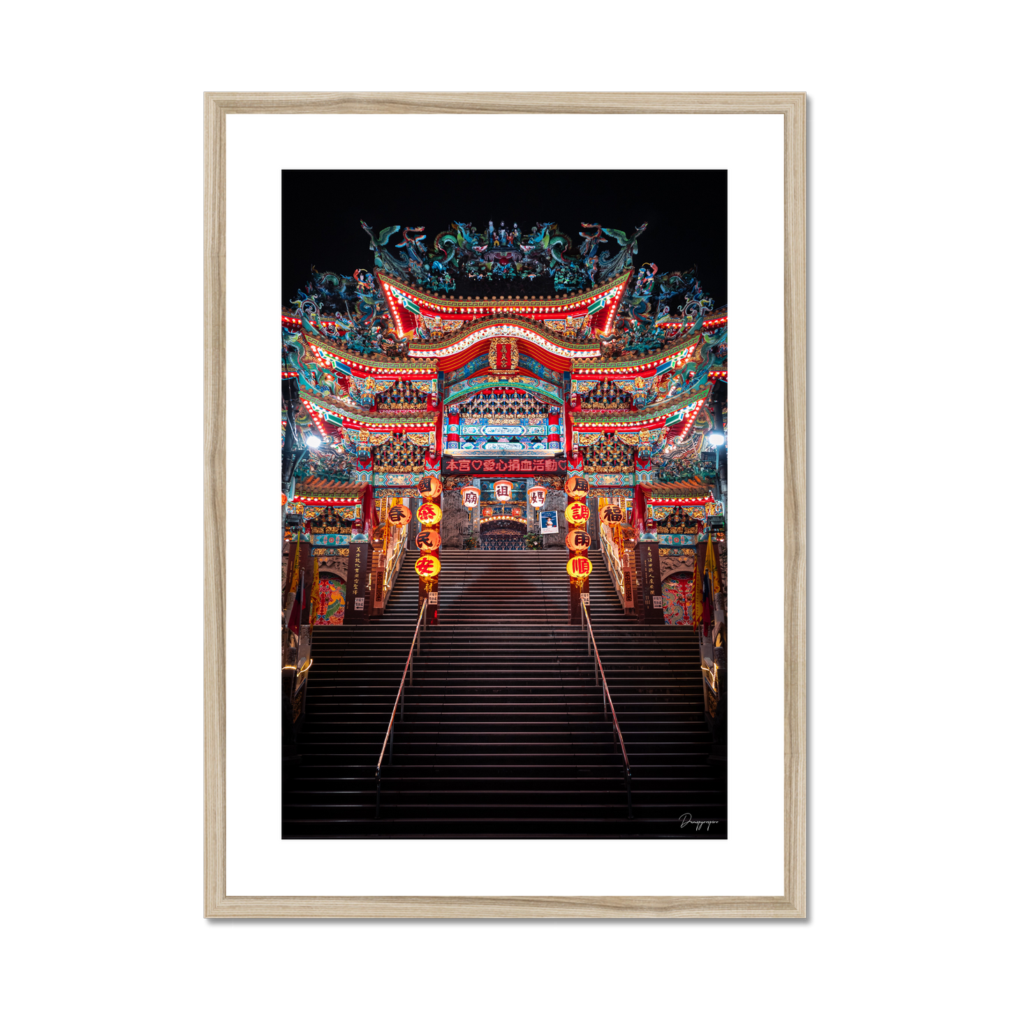 Framed art in a beige wooden frame showing a very impressive Taoist temple with lights that are glowing in the night in Taipei Taiwan