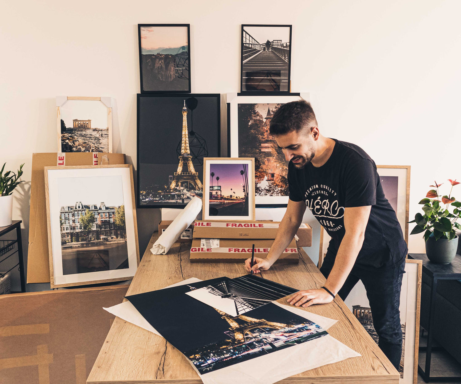 The photographer and artist standing next to a wide range of framed wall art and fine art prints that he has created