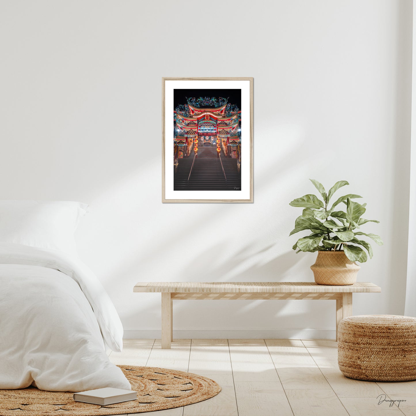 Mockup of wall art showing a big beige wooden frame that is hanging on the wall of a bedroom and contains a photo of a very impressive Taoist temple during the night in Taipei Taiwan