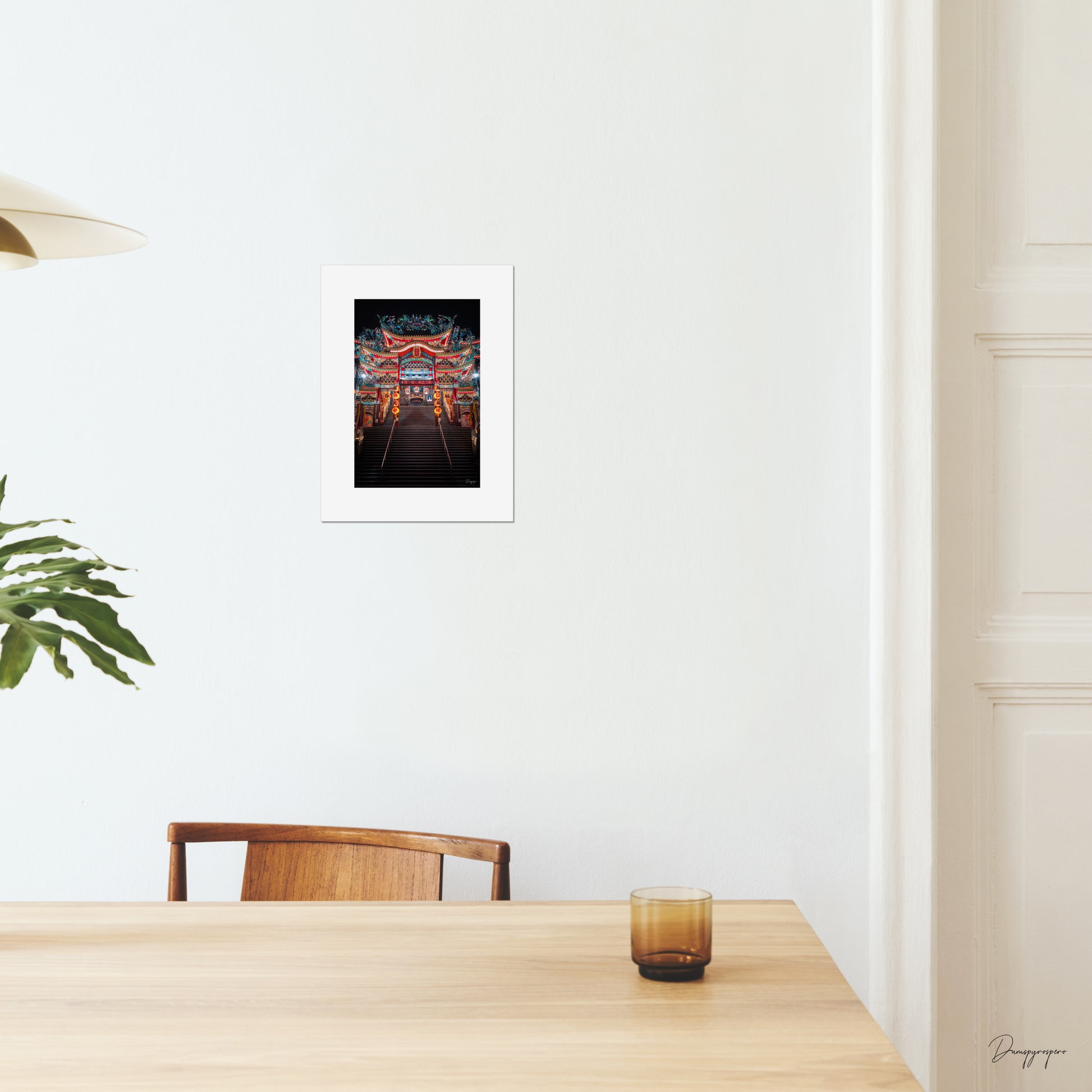 A mockup of a small poster on the wall of a dining room showing a very impressive Taoist temple with lights that are glowing in the night in Taipei Taiwan