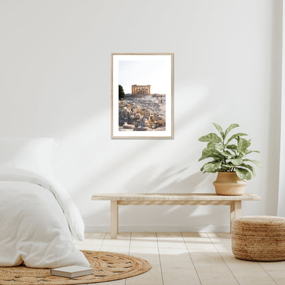 Mockup of wall art showing a big beige wooden frame that is hanging on the wall of a bedroom and contains a photo of the Parthenon on the hill of Acropolis in Athens Greece