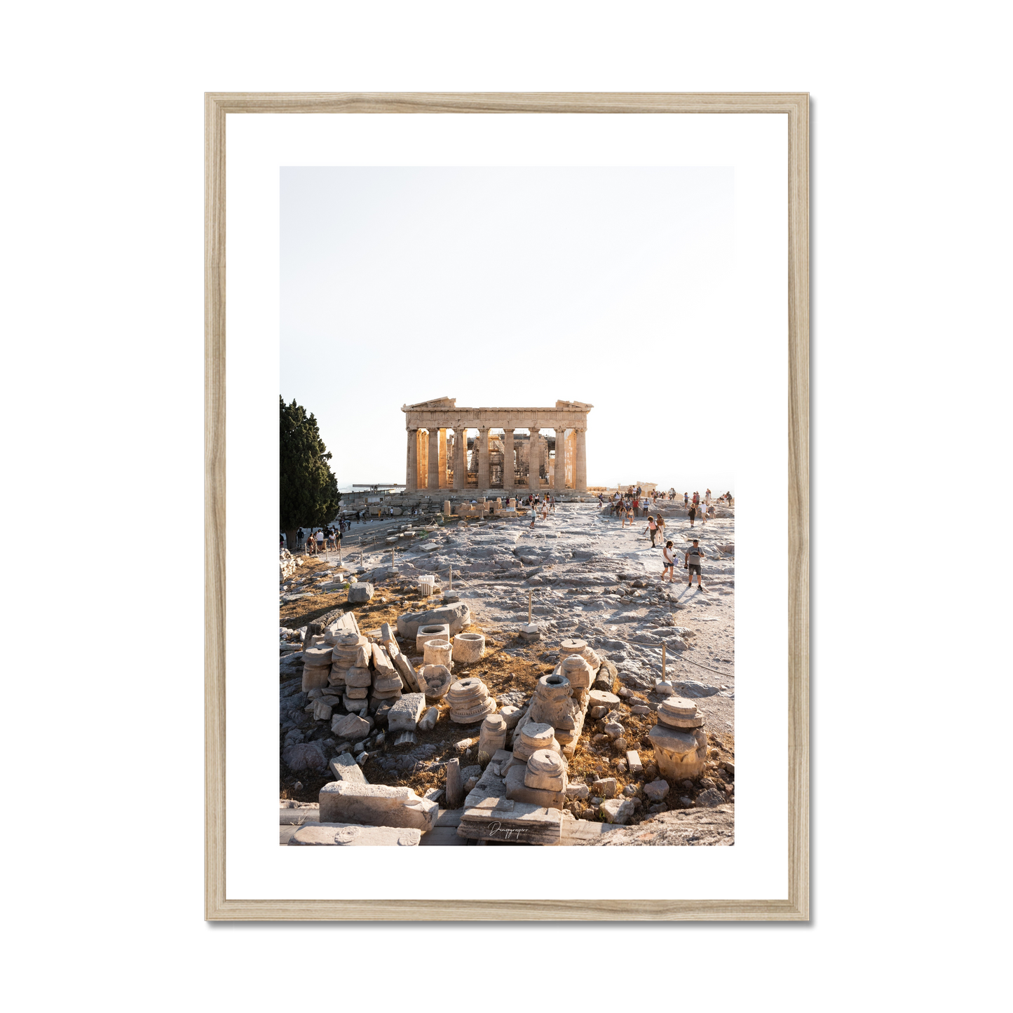 Framed art in a beige wooden frame showing the Parthenon standing behind some ancient ruins on the hill of Acropolis in Athens during a bright warm day